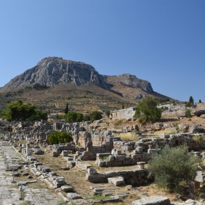 Ruínas arqueológicas com caminho pavimentado e montanhas ao fundo