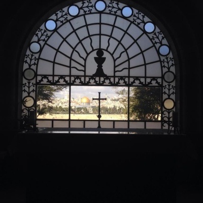 Janela arqueada com moldura em ferro artístico e cruz no meio