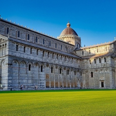 Catedral de Pisa e Torre Inclinada sob céu azul e relvado verde