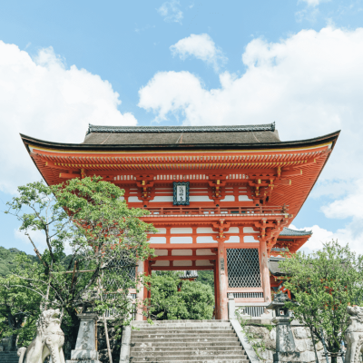 Templo tradicional japonês vermelho e branco com esculturas de pedra e árvores verdes