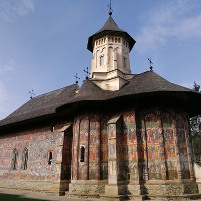 Igreja com murais exteriores coloridos e teto de madeira escuro