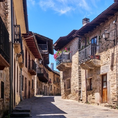 Rua antiga de pedra com varandas e flores sob céu azul