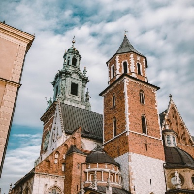 Edifício histórico com torres em tijolo vermelho e branco contra céu nublado