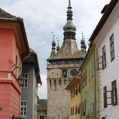 Rua com edifícios antigos e torre histórica colorida ao fundo