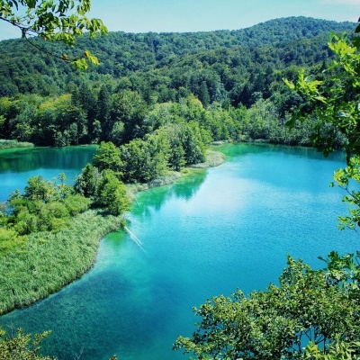 Lago natural com água azul-turquesa e vegetação verde à sua volta.