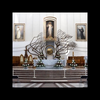 Altar decorado numa igreja com flores brancas e esculturas metálicas abstratas