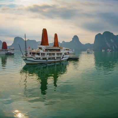 Barcos turísticos em águas calmas com montanhas rochosas ao fundo