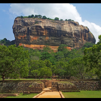 Formação rochosa grande com árvores e um caminho em frente