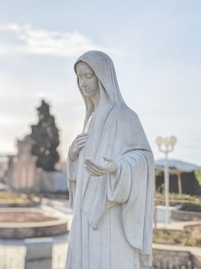 Estátua branca de figura feminina com capuz ao ar livre