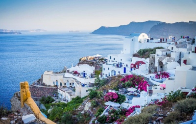 Vila costeira com casas brancas e flores junto ao mar azul