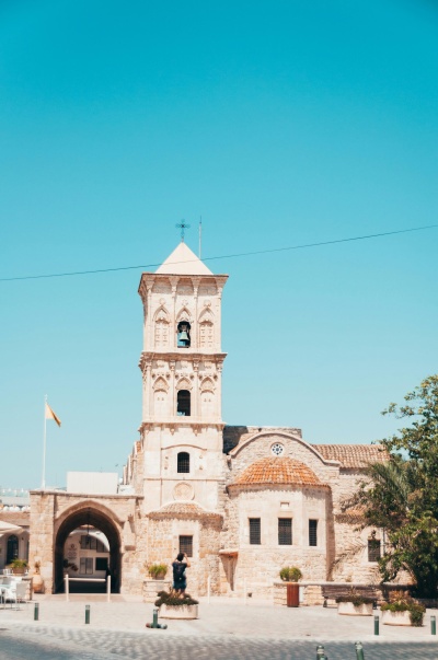 Edifício histórico de pedra com torre sineira e telhado de telha vermelha em dia ensolarado