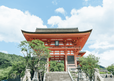 Templo tradicional japonês vermelho e branco com esculturas de pedra e árvores verdes