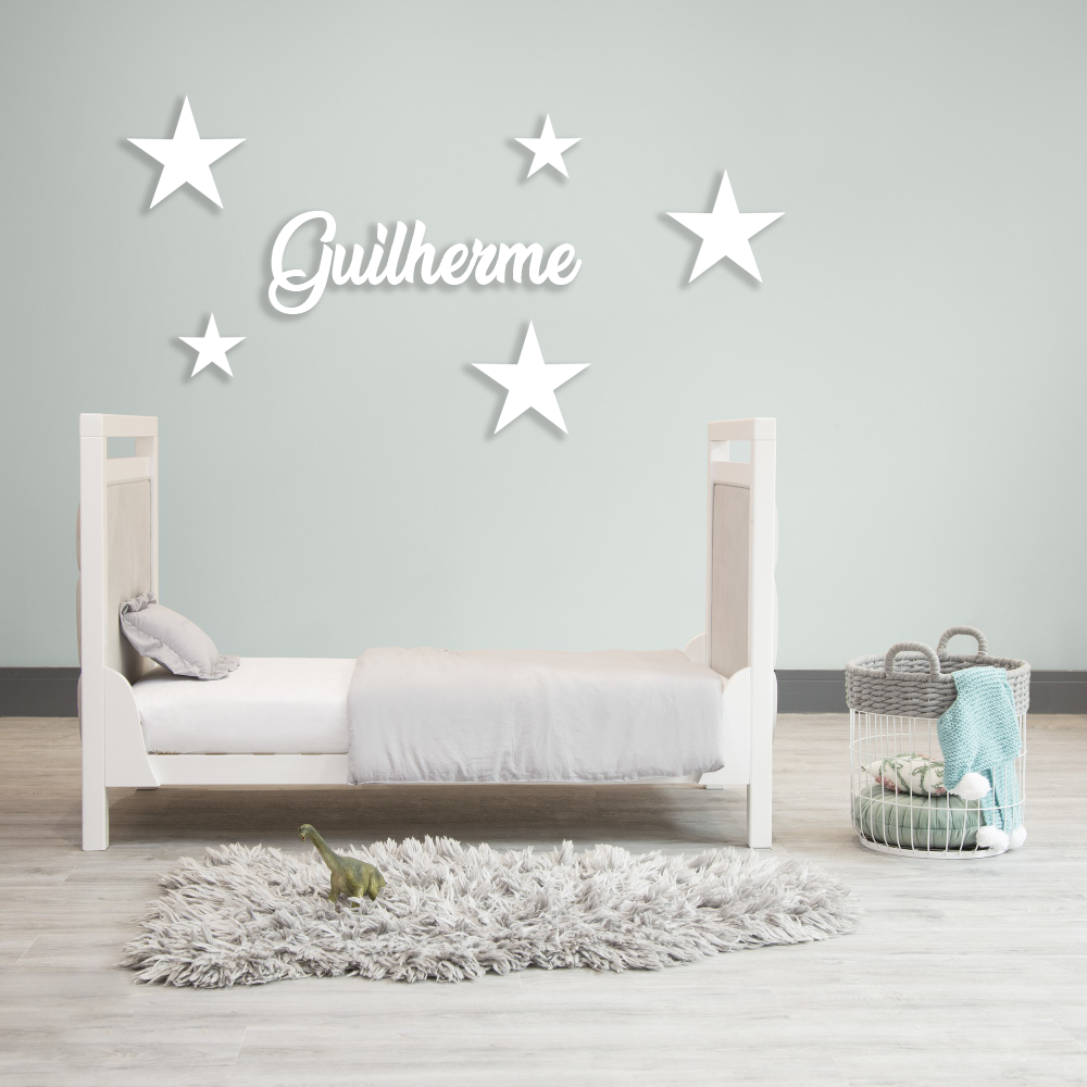 Nome + Estrelas Cama branca de criança com decoração de parede e tapete cinzento felpudo num quarto minimalista.