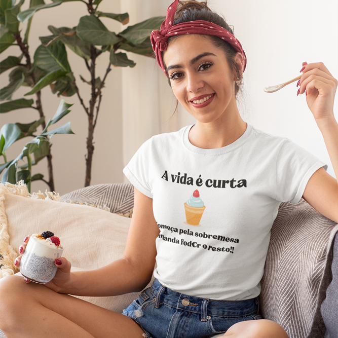 A vida é curta, Começa pela sobremesa e manda fod€r o resto!! Mulher com camisola branca com texto e desenho de gelado sentada num sofá com sobremesa na mão