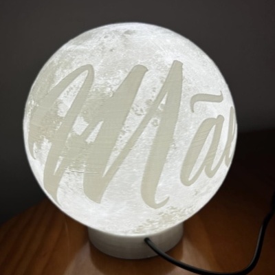 Lâmpada em forma de lua com texto iluminada numa mesa de madeira