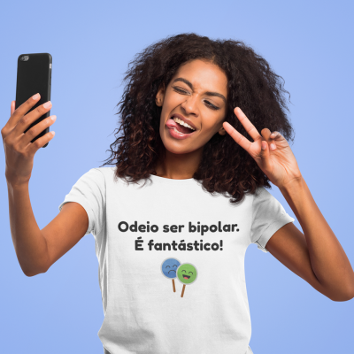 Mulher a tirar selfie com telemóvel, vestindo t-shirt branca com texto e ícones coloridos
