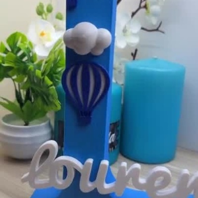 Letra decorativa azul com balões, nuvens e nome personalizado branco
