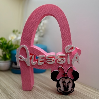Objeto decorativo cor-de-rosa com a letra A, nome ALESSIA em letras brancas e cabeça da Minnie