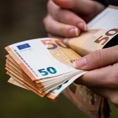 Mãos segurando várias notas de 50 euros