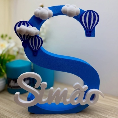 Objeto decorativo de espuma azul com nuvens e balões e palavra Simão