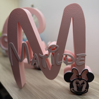 Letra rosa texturada com nome Matilde e Minnie com laço cor de rosa.
