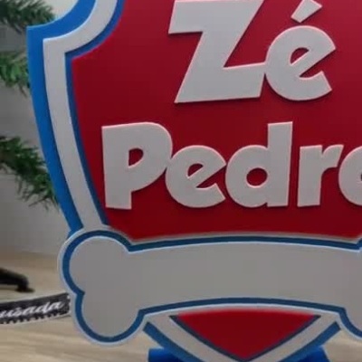 Suporte em forma de escudo vermelho com borda azul e texto Zé Pedro em branco