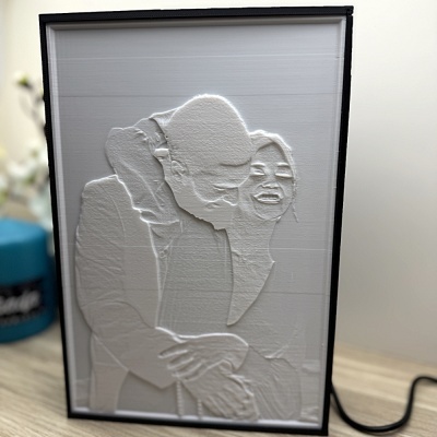 Retrato em relevo branco com casal sorridente em moldura preta