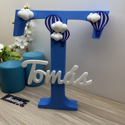Letra decorativa azul com nome Tomás e balões de ar quente e nuvens brancas