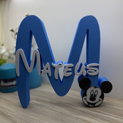 Decorativo letra M azul com o nome MATEUS e figura do Mickey Mouse numa mesa