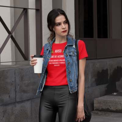 Mulher com t-shirt vermelha, colete de ganga e calças pretas segura copo branco