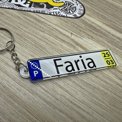 Chaveiro placa com texto Faria em superfície de madeira clara