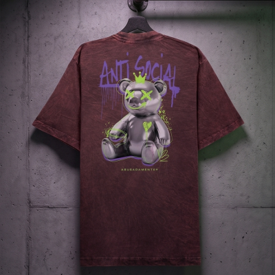 T-shirt castanha com estampa de urso cinzento e texto colorido pendurada numa parede cinzenta