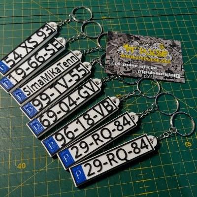 Conjunto de chaveiros com design de matrículas portuguesas sobre superfície de corte verde
