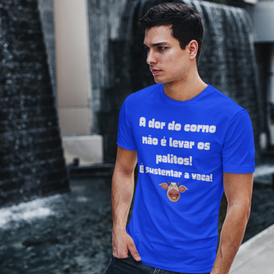 Homem com t-shirt azul com texto branco e ilustração de vaca perto de fonte de água