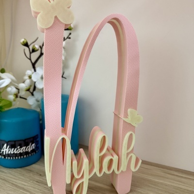 Suporte decorativo rosa e branco com nome Nylah em letras cursivas e borboletas