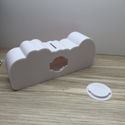 Dispositivo branco em forma de nuvem com peça redonda destacada sobre mesa de madeira