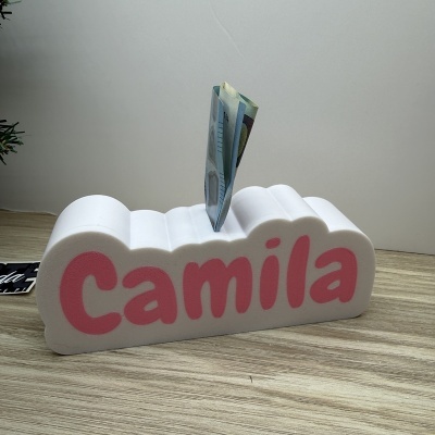 Cofre branco em espuma com nome Camila em letras cor-de-rosa e nota de euro azul inserida no topo