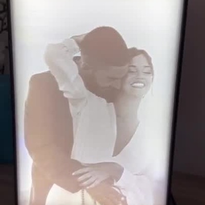 Moldura digital com imagem 3D que se ilumina para mostrar foto colorida de um casal abraçado