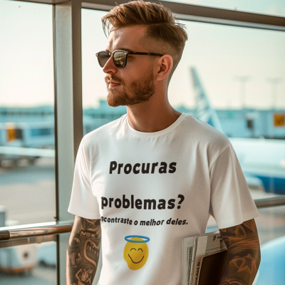 Homem com camisola branca com dizeres e emoji, óculos escuros, tatuagens, em área de aeroporto
