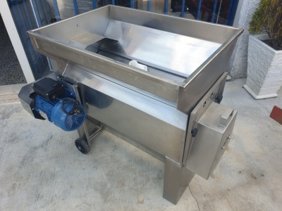 Máquina industrial em metal inoxidável com motor elétrico azul em chão de cimento