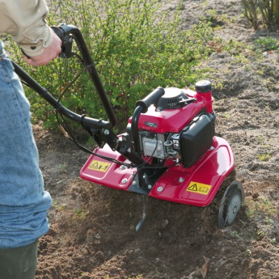 Máquina de rastelo a motor vermelha para jardim em uso