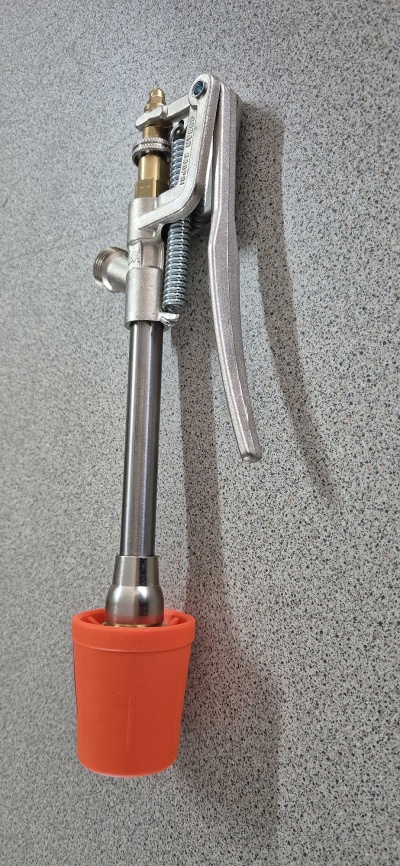 Bico de pulverização metálico com base laranja sobre superfície cinza