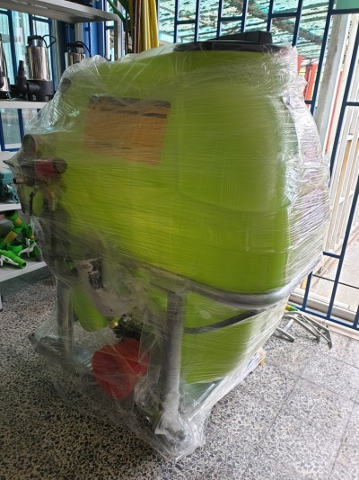 Máquina agrícola de pulverização verde embalada em plástico transparente em ambiente interior com piso de mosaico.