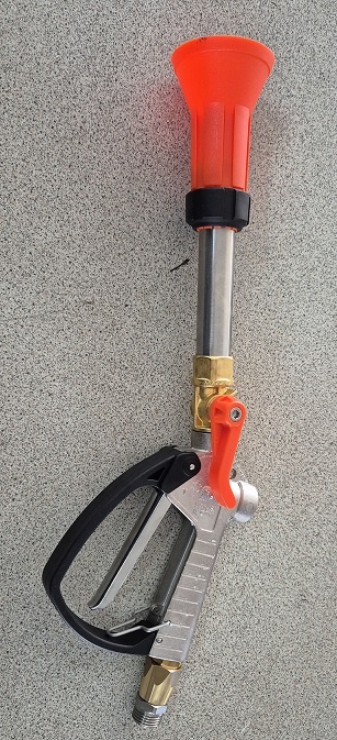 Pistola de limpeza de alta pressão em metal e plástico laranja sobre superfície cinzenta