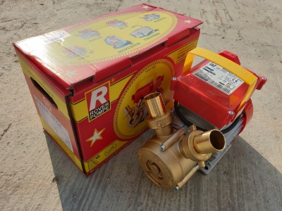 Bomba de água metálica com motor e caixa vermelha em chão de cimento