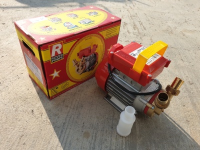 Bomba de água metálica vermelha com pega amarela e acessórios em latão junto a frasco branco e caixa colorida.