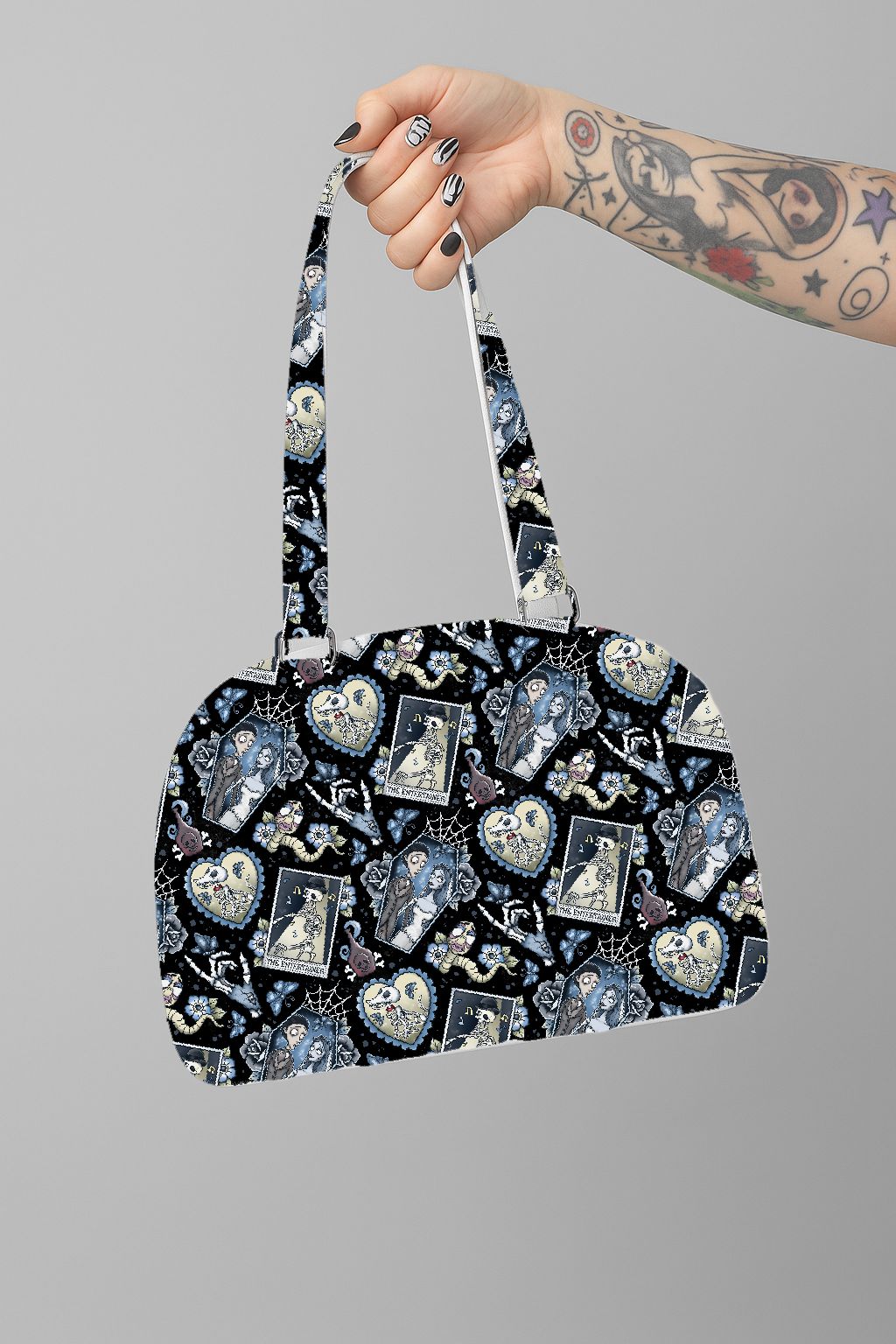 Mala de mão com padrão colorido segurada por uma mão tatuada