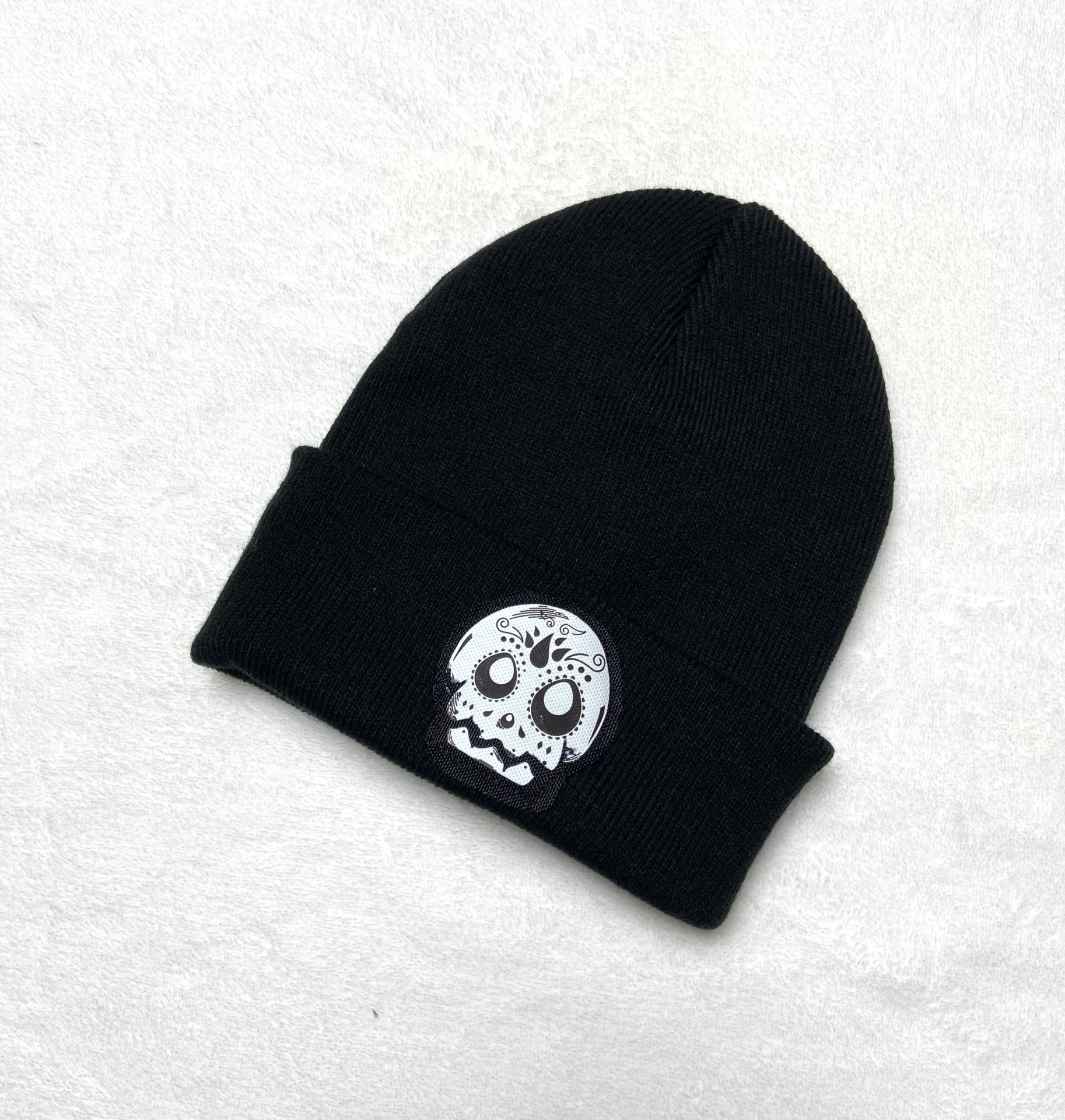Gorro preto de malha com patch de caveira branca estilizada