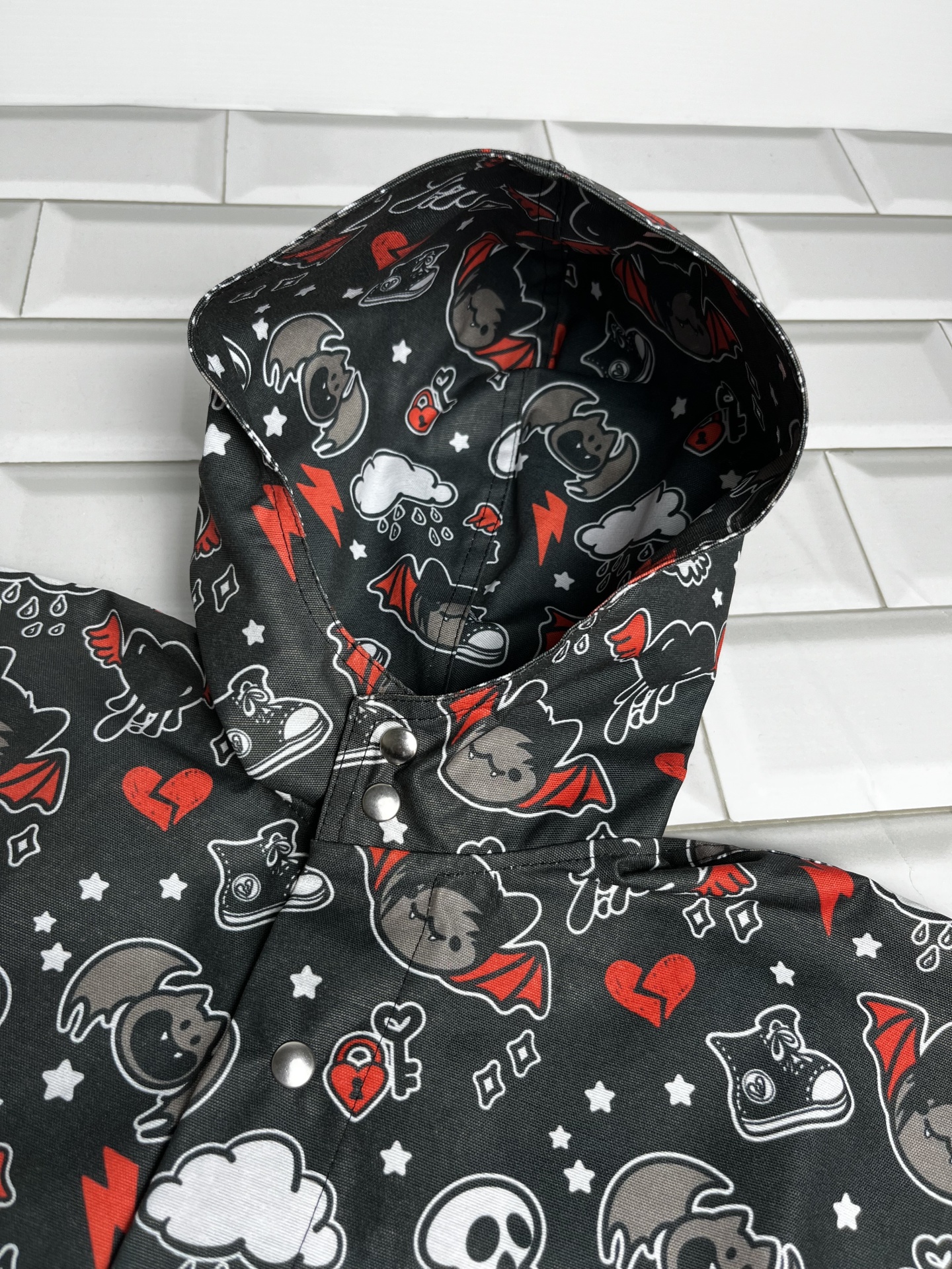 Casaco impermeável preto com padrão de gatinhos e símbolos coloridos