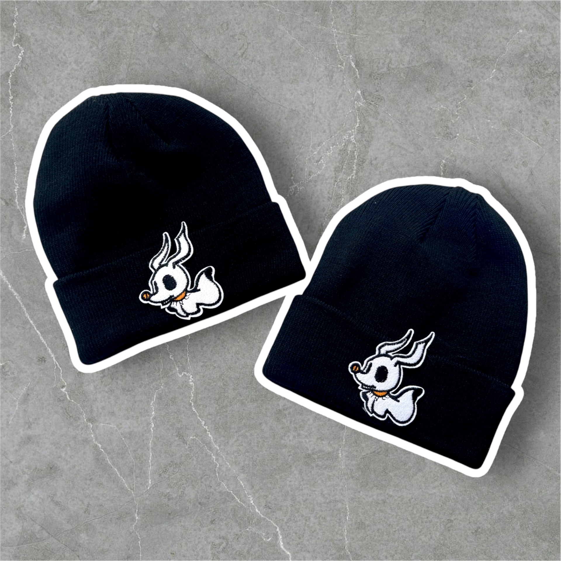 Duas boinas pretas de malha com bordado branco de personagem e olhos negros